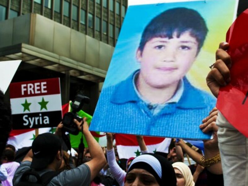 People carrying the photo of Hamzah al-Khatib during a solidarity march with the Syrian people in Montreal.