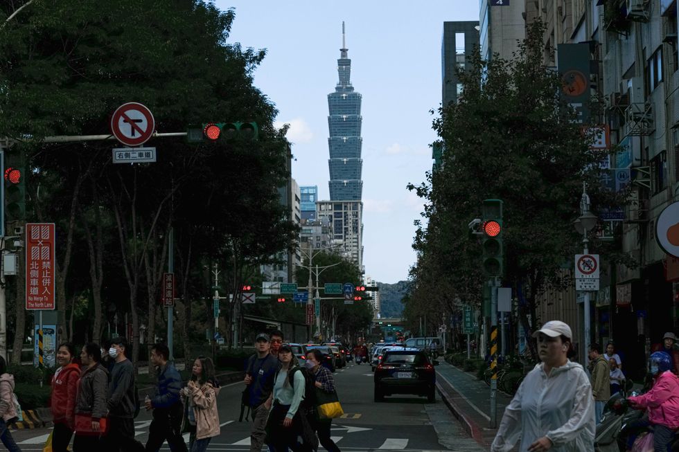 People cross a street in downtown area of Taipei.