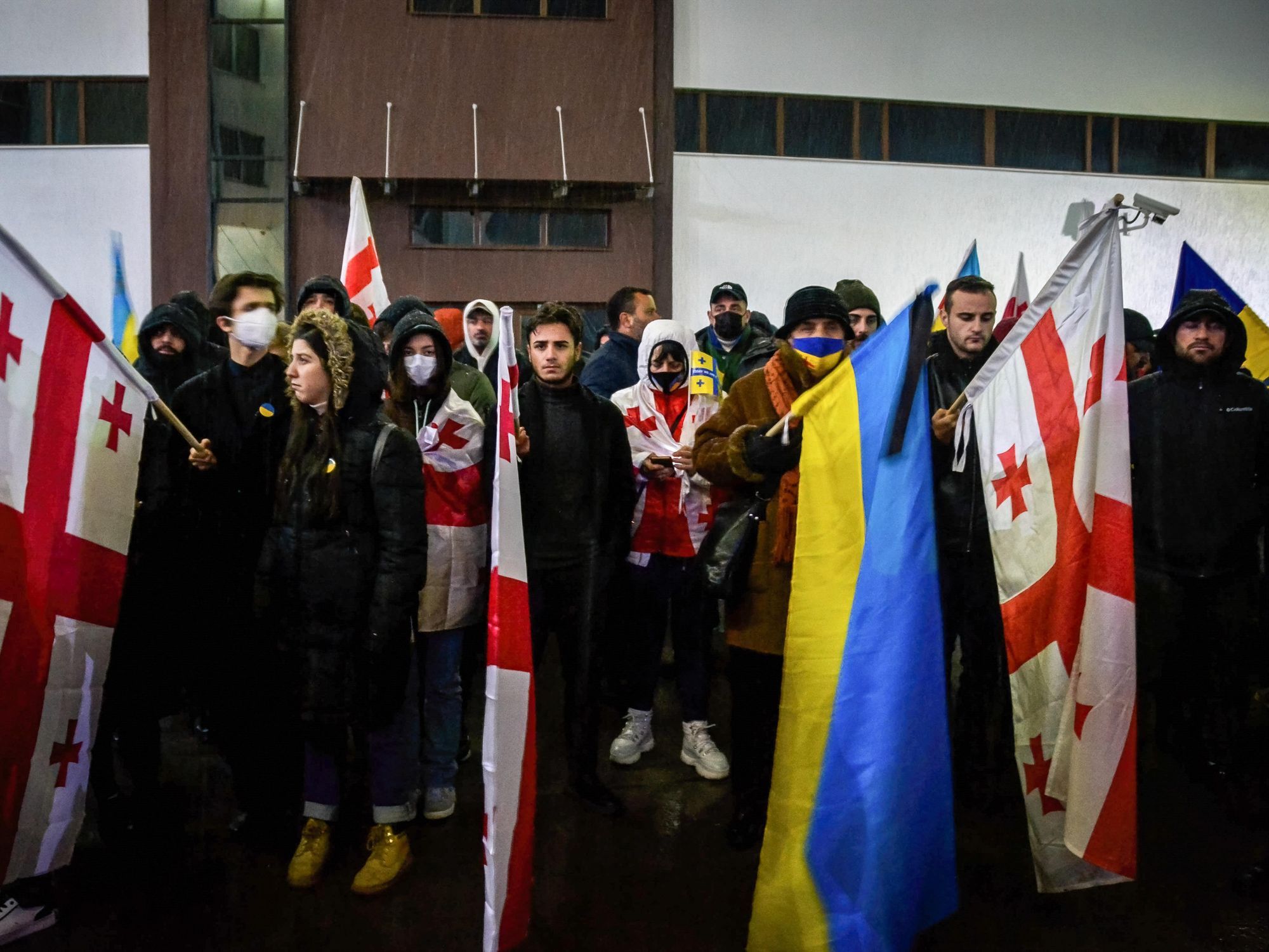 people holding ukrainian and georgia flags