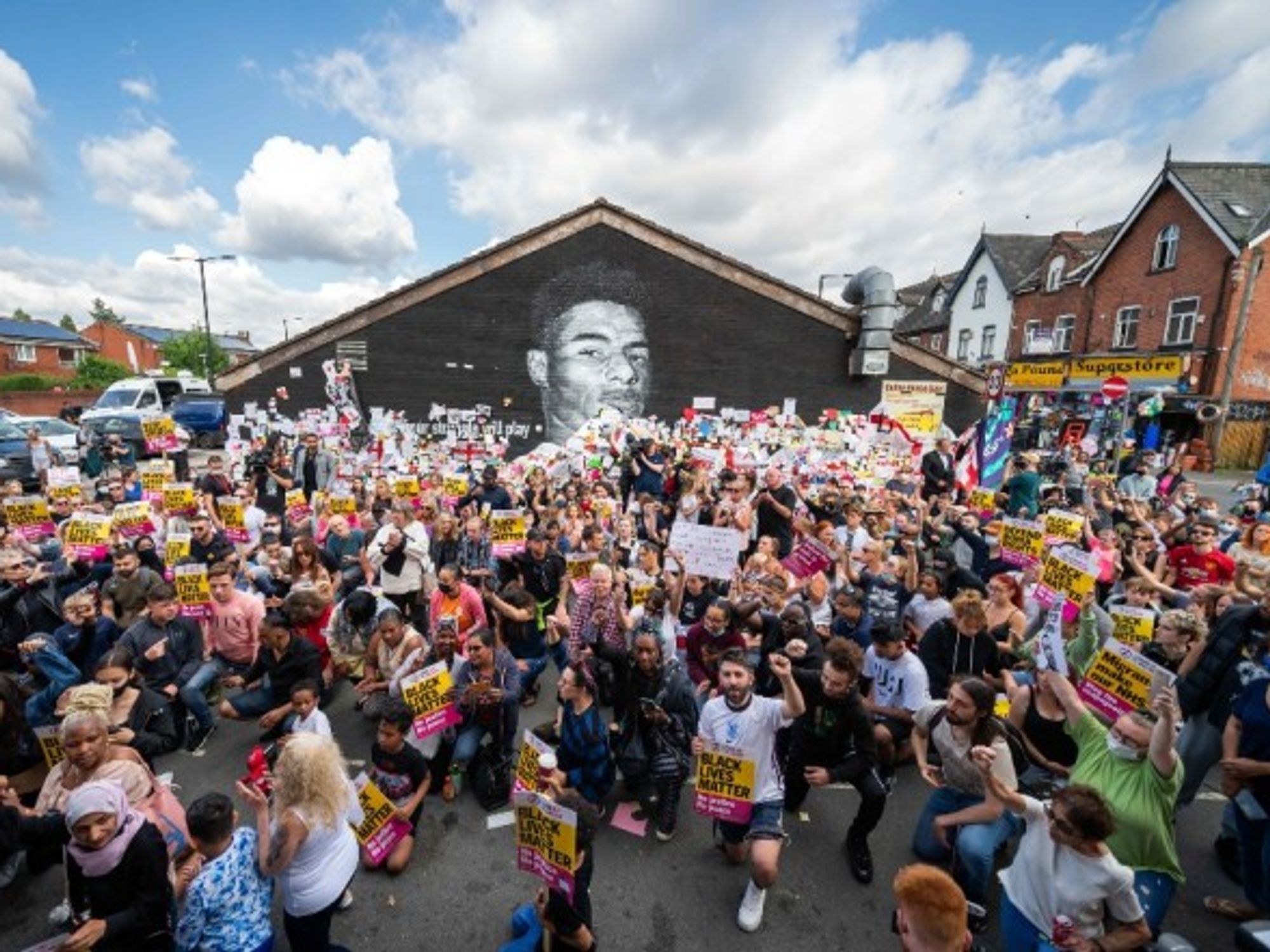 People kneel in front of a mural of Manchester United striker Marcus Rashford