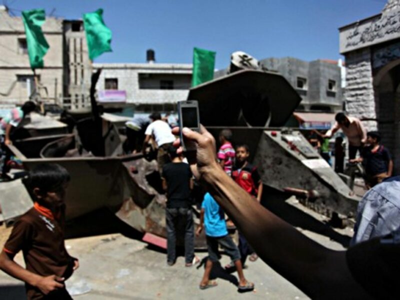 People on the remains of a destroyed Israeli military vehicle in the Gaza Strip
