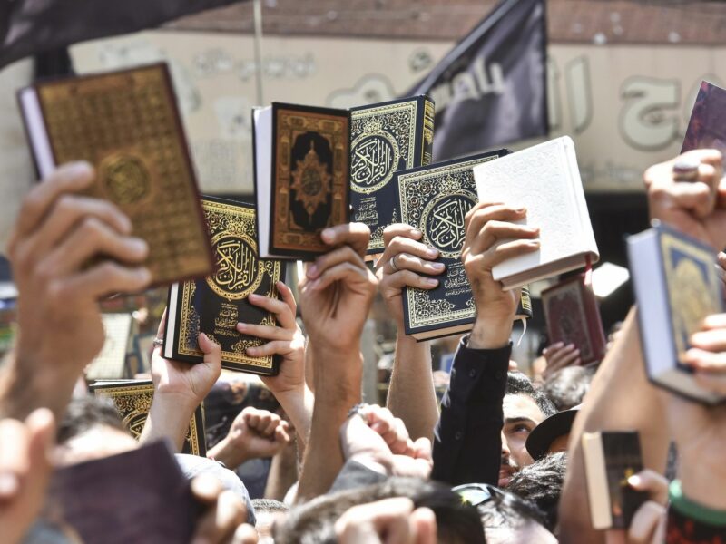 People raise copies of the Koran as they participate in a demonstration