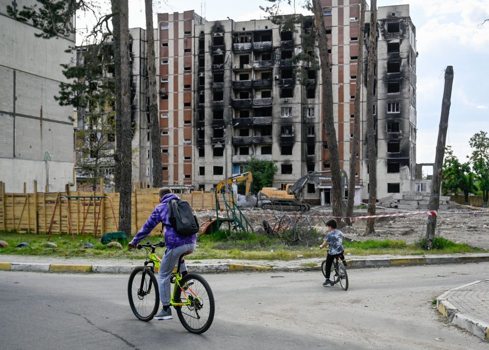 People ride bikes near an apartment building damaged by Russian shelling in Irpin, Ukraine.