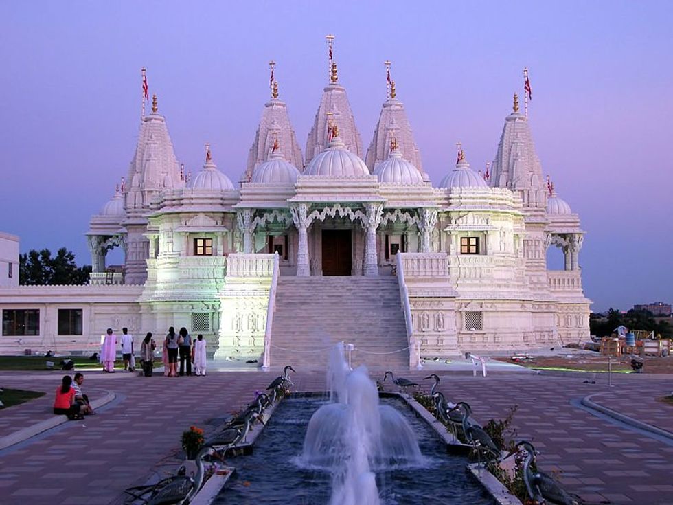 People sitting next to a fountain in front of the BAPS Shri Swaminarayan Mandir Hindu temple in Etobicoke, Toronto