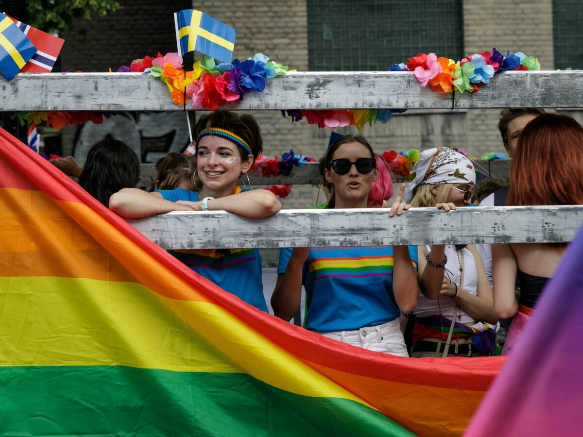 People smile in the back of a truck surrounded by pride flags and memorabilia in Poland