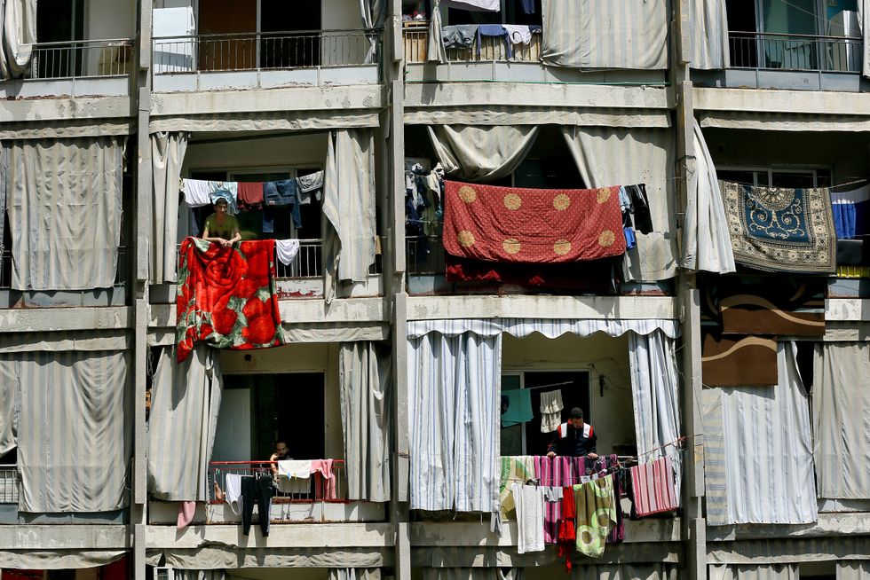 People stand on their balconies at a residential building in Beirut.