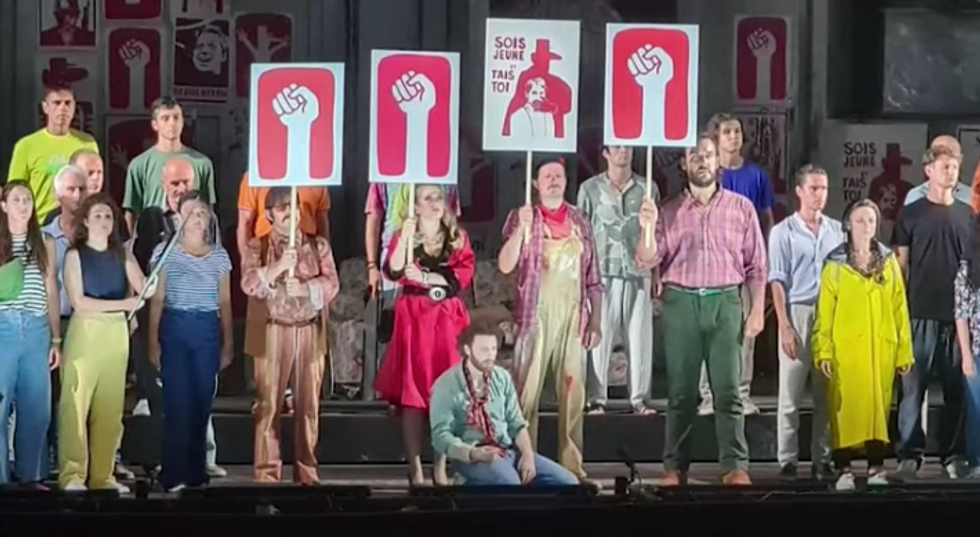 People standing with signs at the Puccini Festival.