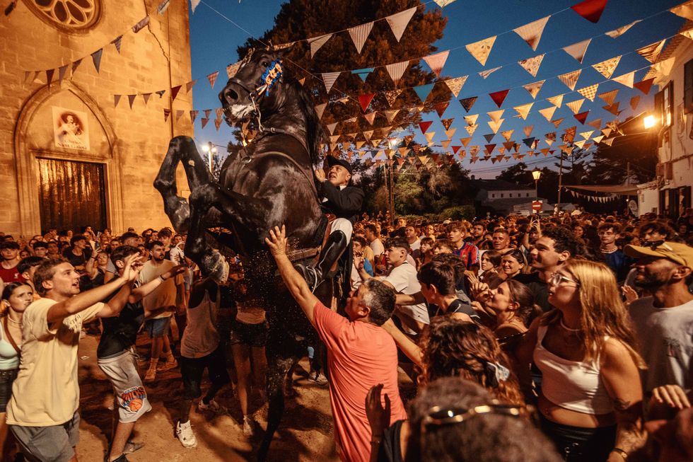 People surrounding a horse as they take part in a traditional "Jaleo" at the Sant Gaieta Festival in Llucmacanes.