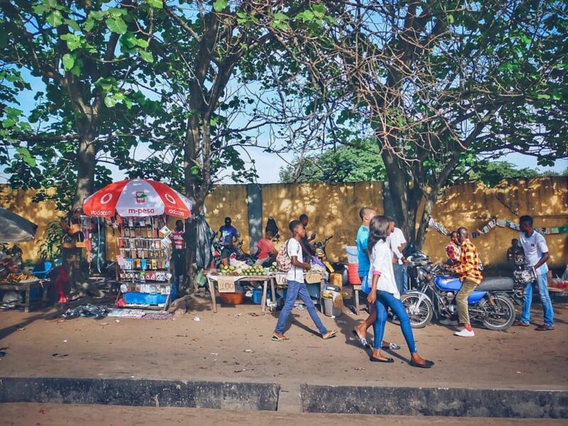 People walk past a street market selling accessories and produce