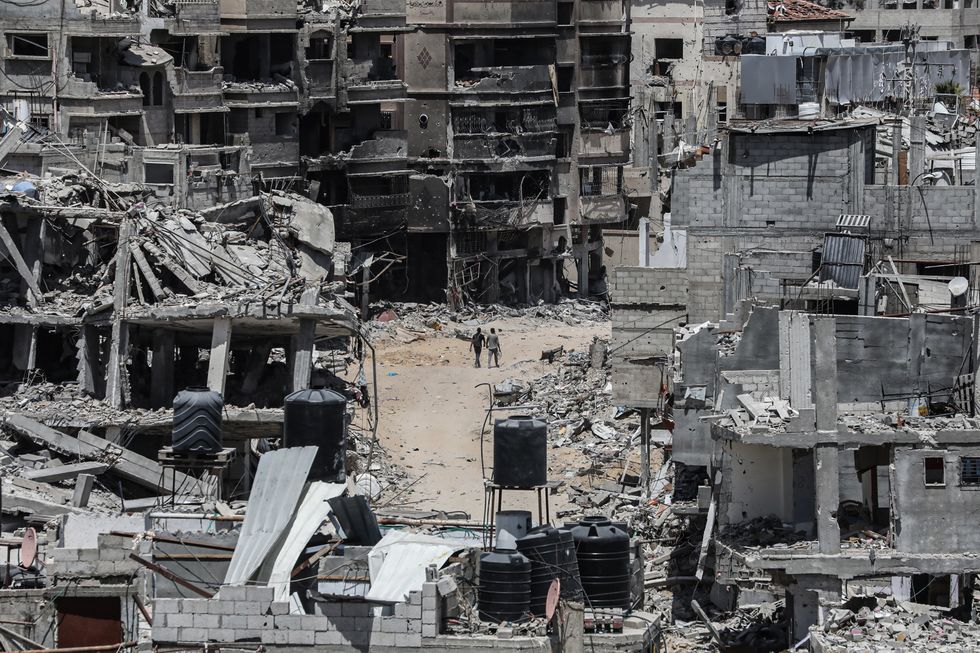 People walk past destroyed buildings in Khan Yunis in the southern Gaza Strip on April 21, 2024