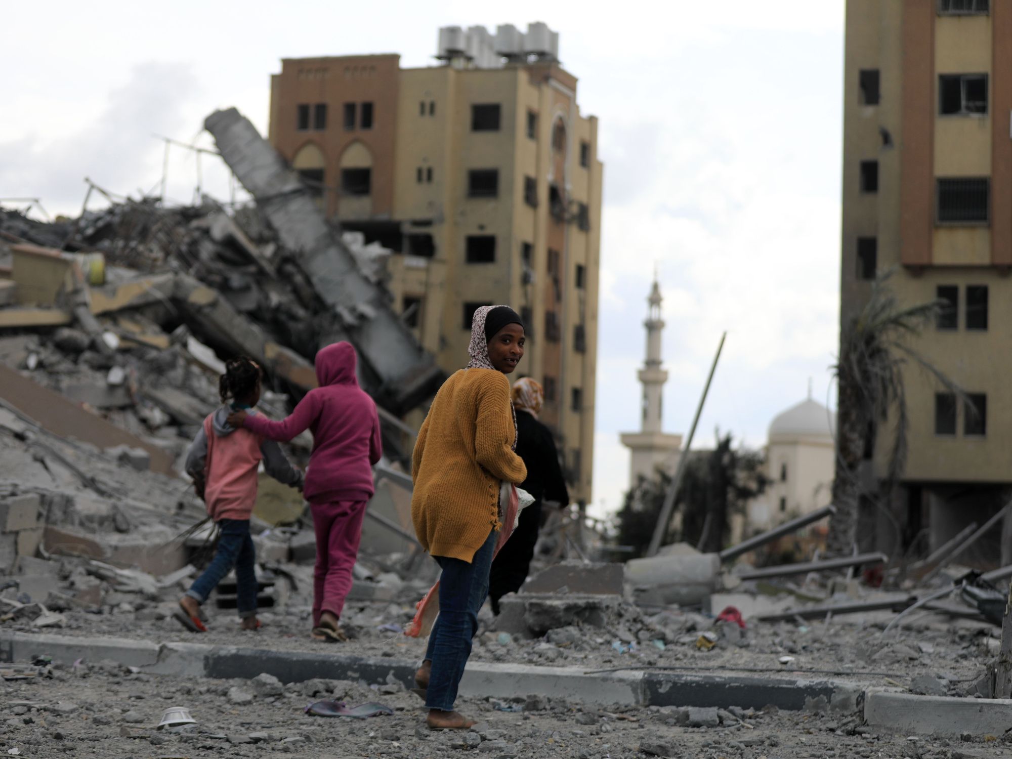 People walk past destroyed buildings in the central Gaza Strip, on March 25, 2024.