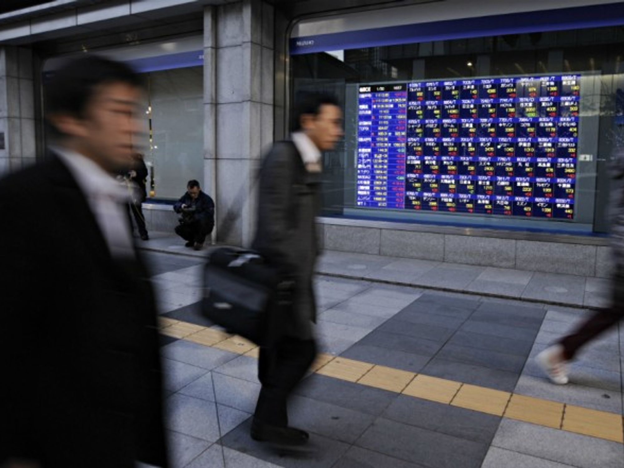 People walking by an electronic board showing stock indexes on Jan. 30, 2013 in Tokyo, Japan