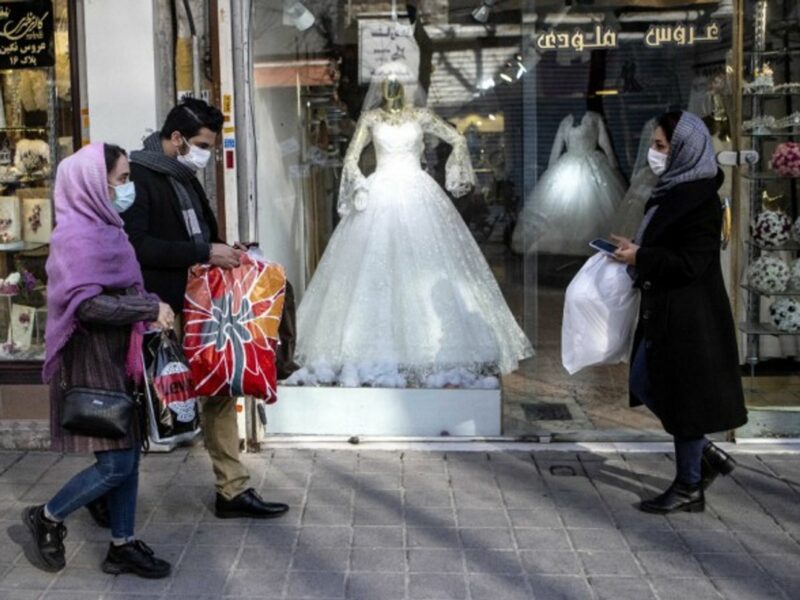 People walking past a closed wedding dress store in Tehran, Iran