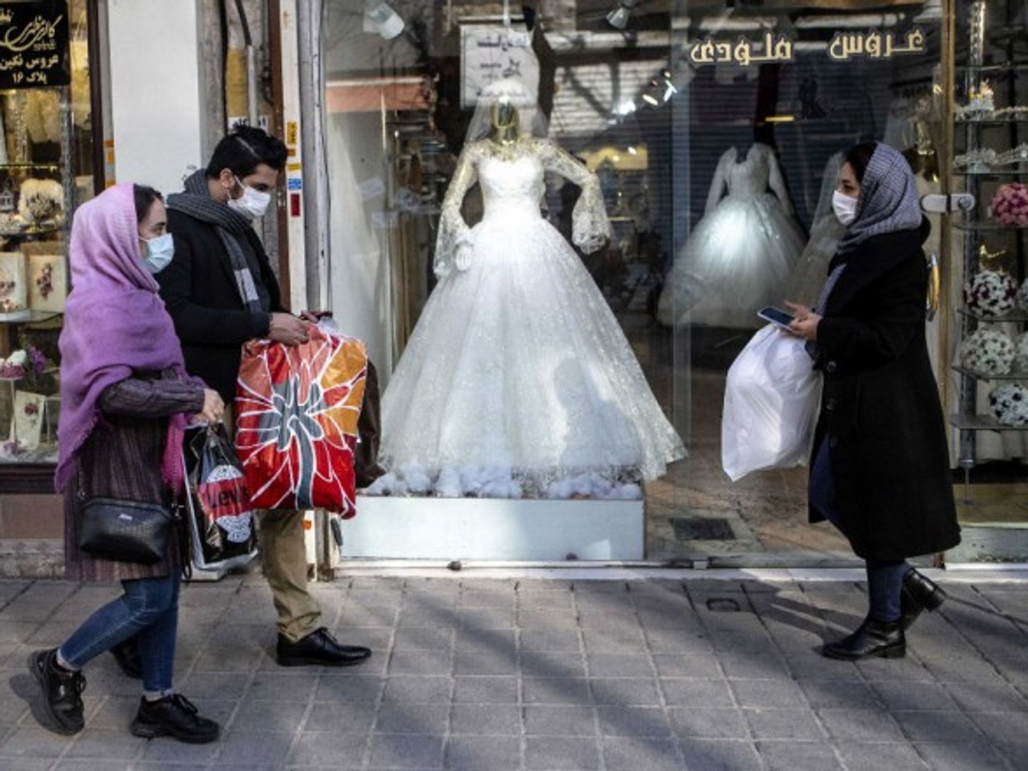 People walking past a closed wedding dress store in Tehran, Iran