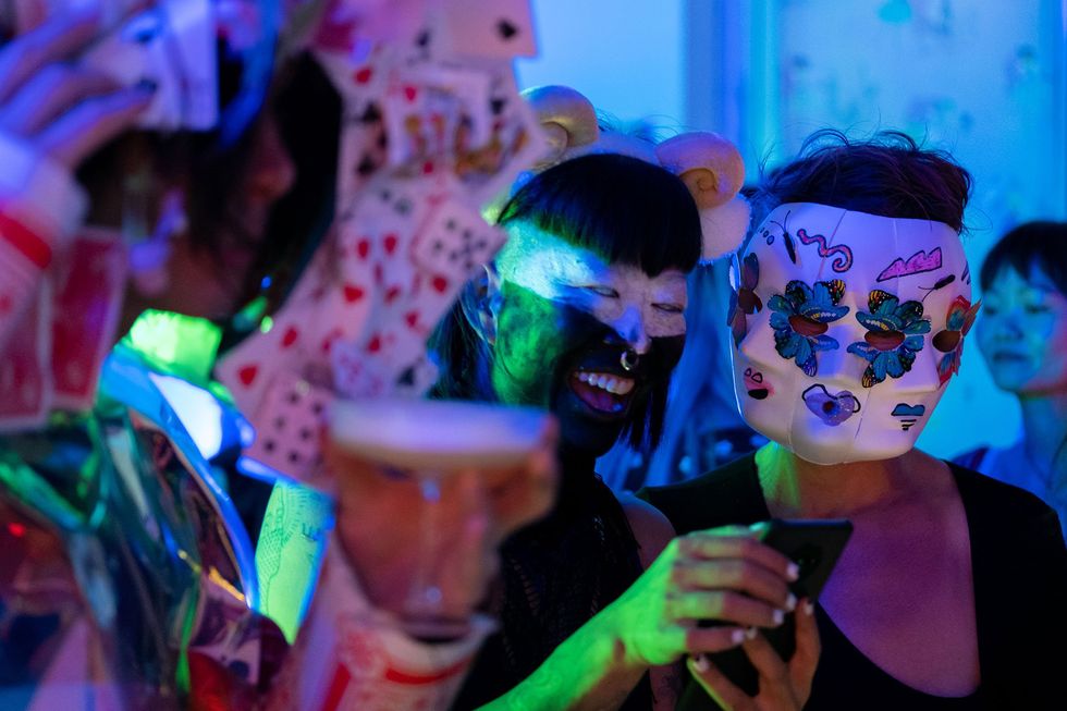 People wearing bezar masks for a party someplace with a blue lighting