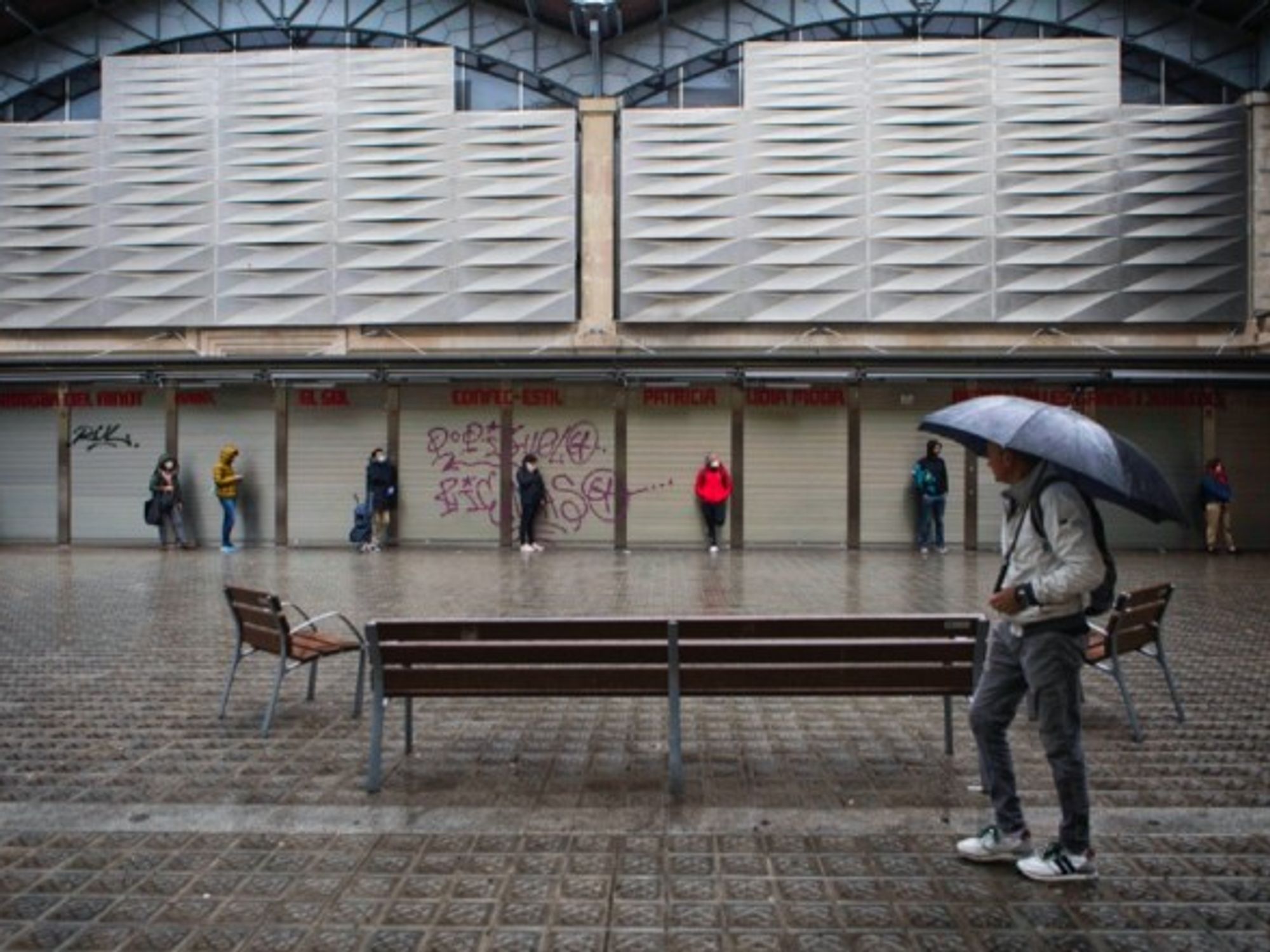 People wearing face masks wait in line to enter a grocery store in Barcelona, Spain.