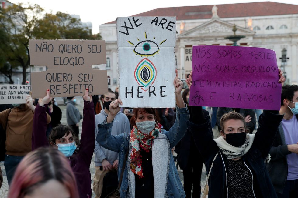 People wearing protective face masks and holding signals take part in a rally to mark the International Women's Day in Lisbon, Portugal, on March 8, 2021.