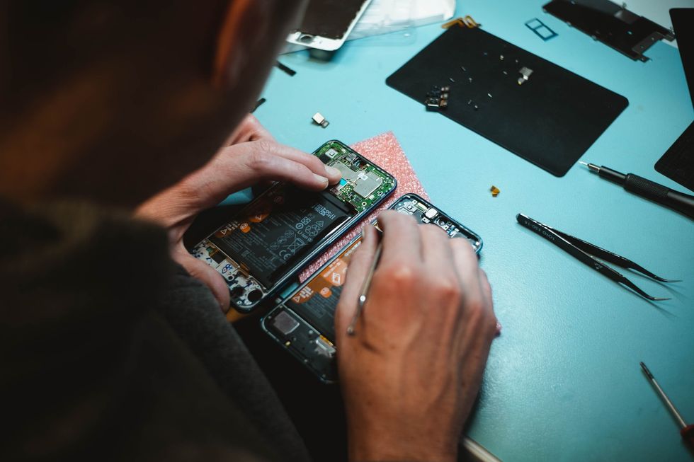 Person repairing a smartphone under a lighted table