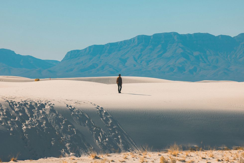 Peson walking in white sand desert during day time.