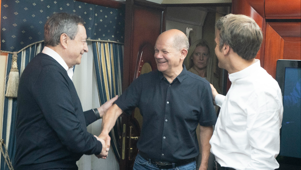 Phot of ​Draghi and Macron greeting Scholz on their train to Ukraine