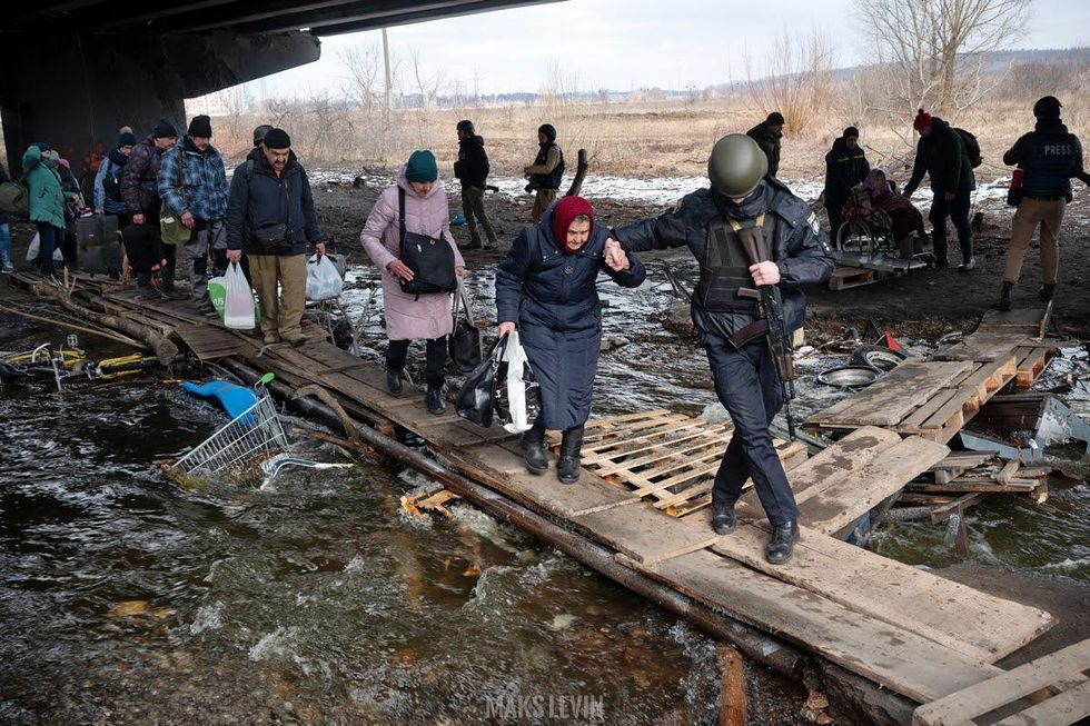 Photo by Maks Levin of a soldier helping people cross a flooded area