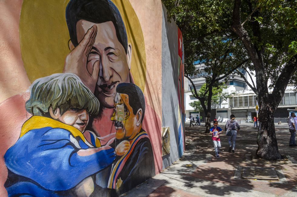 Photo fo a mural in Caracas, Venezuela, depicting President Maduro carrying a child, with late leader Hugo Chavez in the background