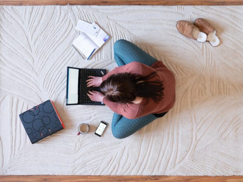 photo from above of a woman on the floor working on her computer