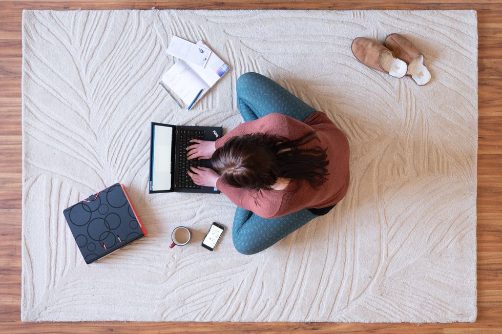 photo from above of a woman on the floor working on her computer