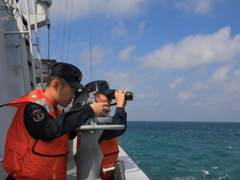 photo of 2 navy sailors looking into ocean with devices