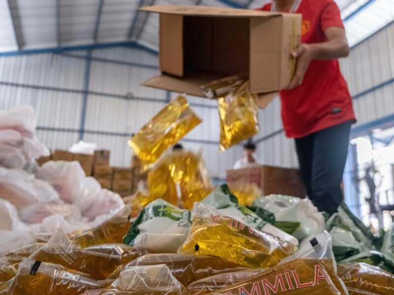 Photo of a a person unloading packs of cooking oil, to be sold as as part of basic food packages at affordable prices in Indonesia