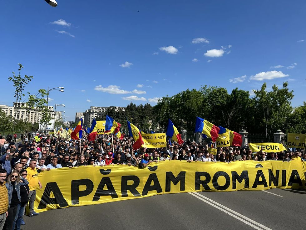 Photo of a AUR protest in Bucharest with Romanian flags and anti-government and anti-Western slogans.