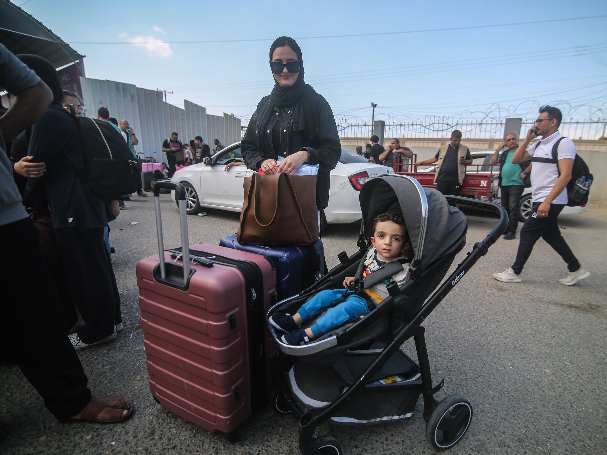 photo of a baby in a stroller and his mother with a suitcase