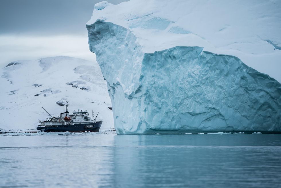 Photo of a boat approaching a large iceberg in the Arctic Ocean