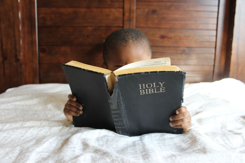 photo of a boy reading a bible