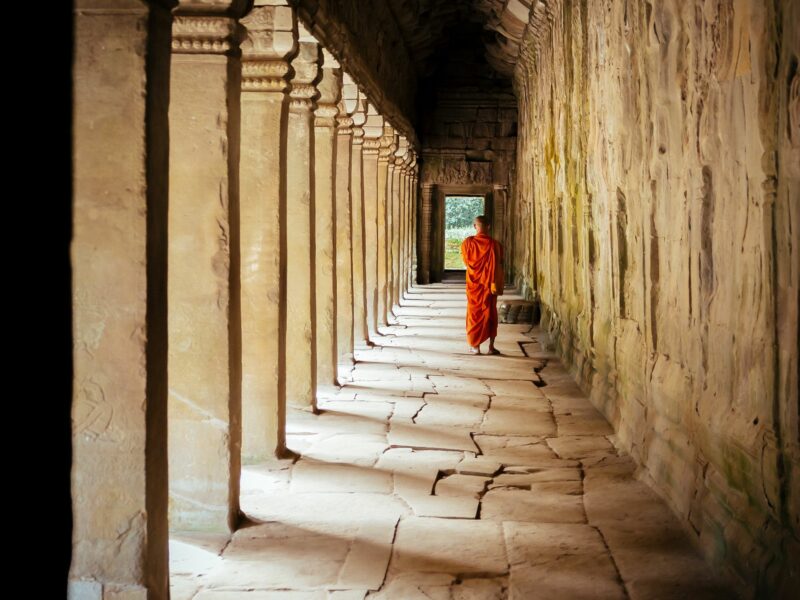 Photo of a Buddhist monk in a Cambodia temple, walking away from the camera