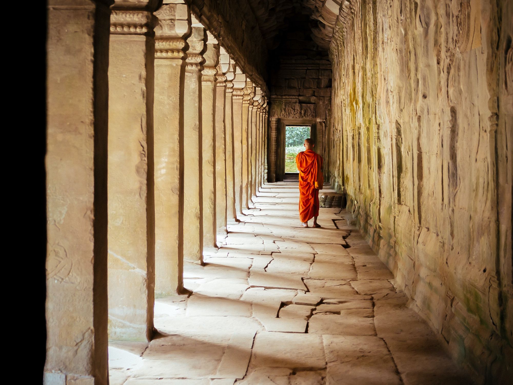 Photo of a Buddhist monk in a Cambodia temple, walking away from the camera