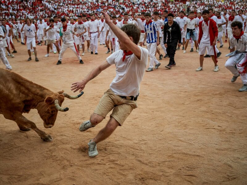 Photo of a bull charging a man during San Fermín festivities in Pamplona, Spain