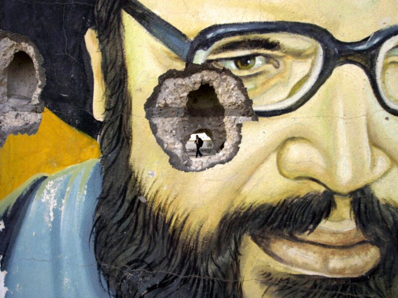 Photo of a bullethole in a mural depicting Hezbollah leader Hassan Nasrallah.