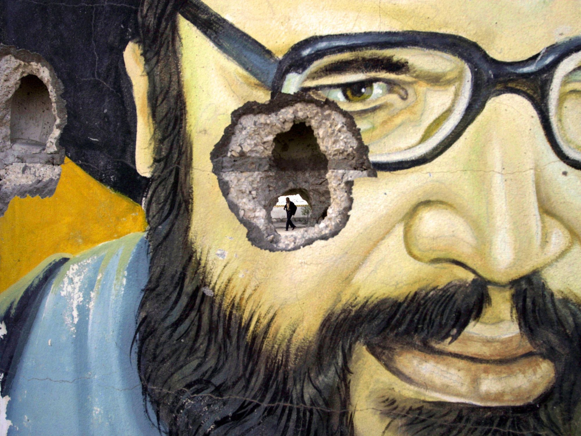 Photo of a bullethole in a mural depicting Hezbollah leader Hassan Nasrallah.
