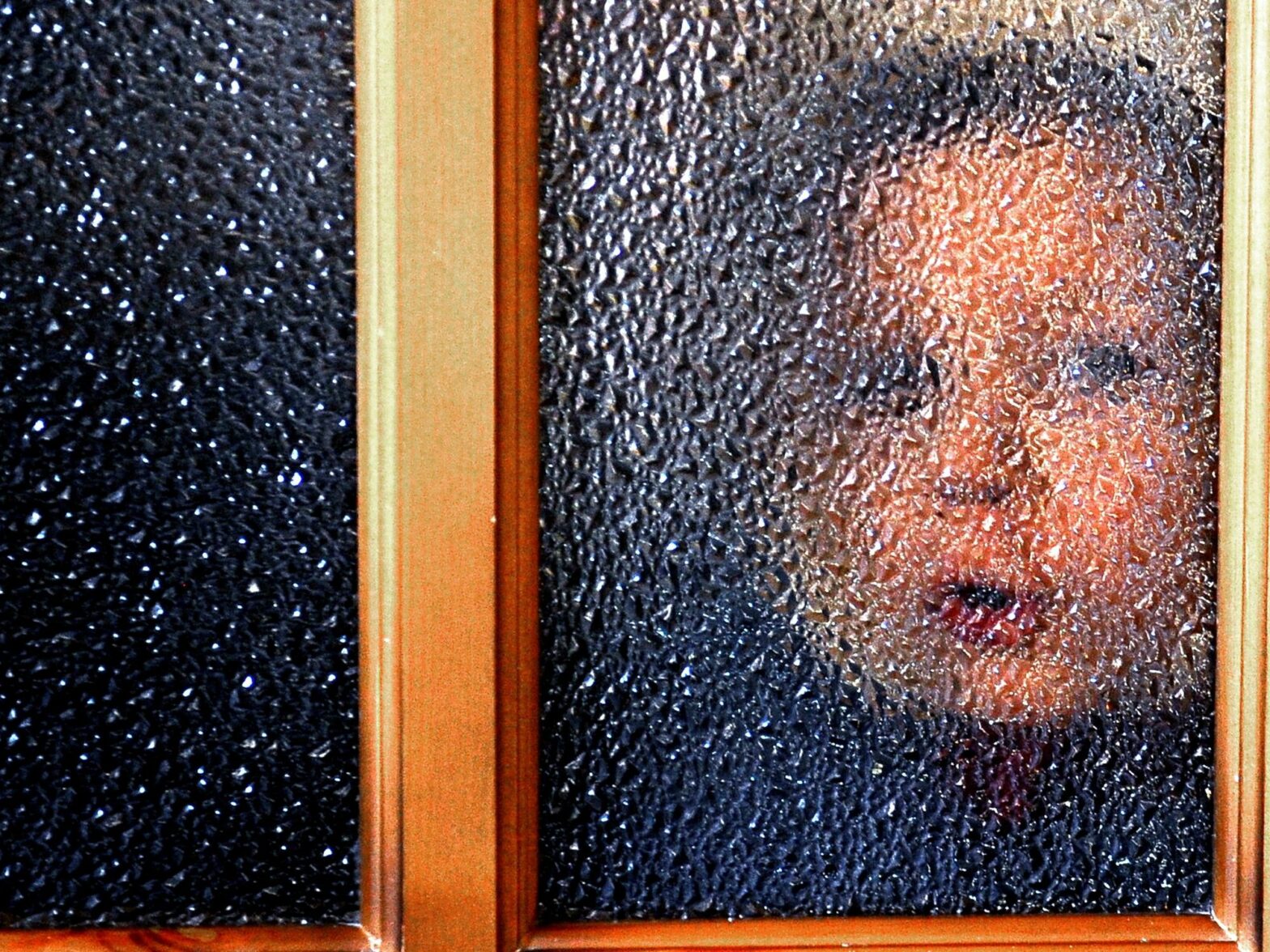 Photo of a child looking through a window at Donetsk's Orphanage