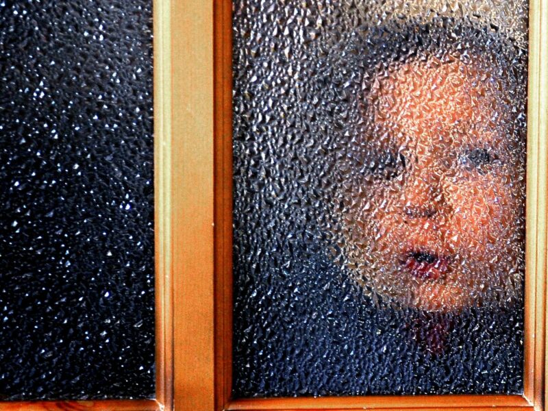 Photo of a child looking through a window at Donetsk's Orphanage