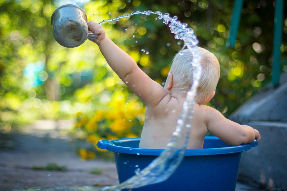 Photo of a child playing with water in the summer