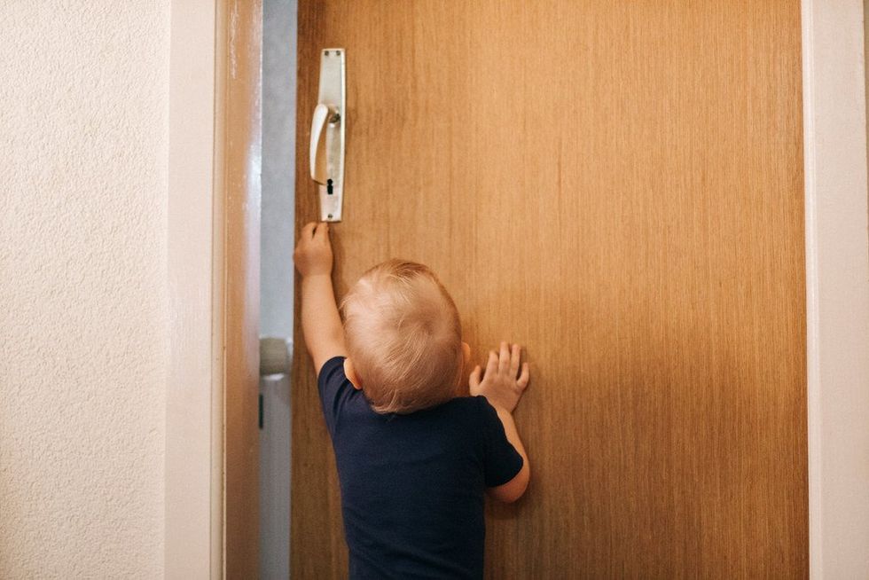 Photo of a child reaching for a door handle.