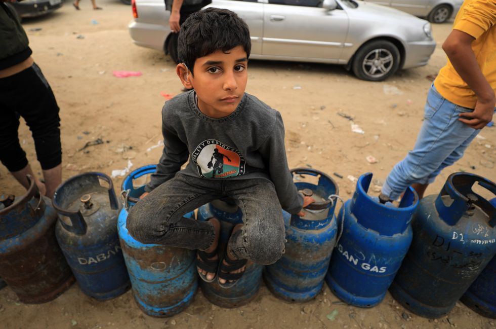 Photo of a child sitting on a gas cylinder waiting to fill it up in Southern Gaza