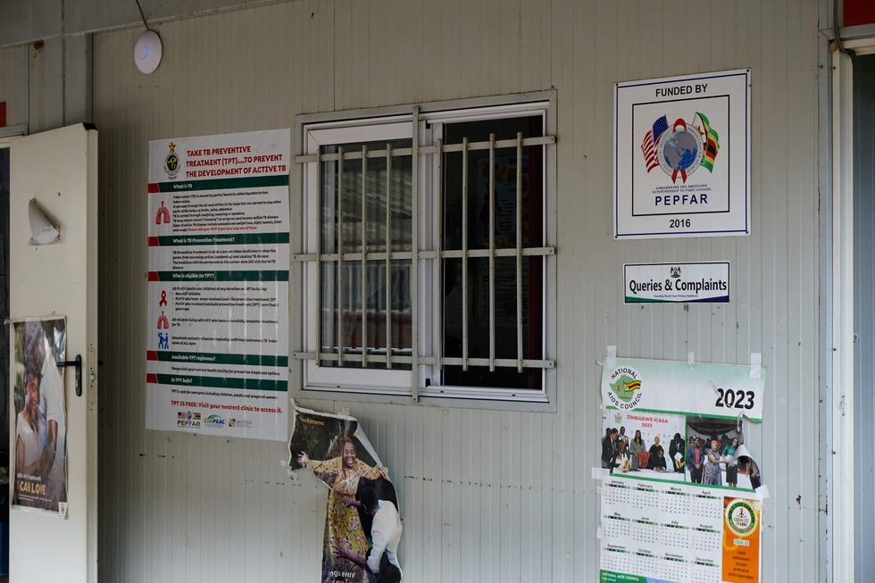 Photo of a corner store with a bunch of posters and a calendar. The windows are barred.