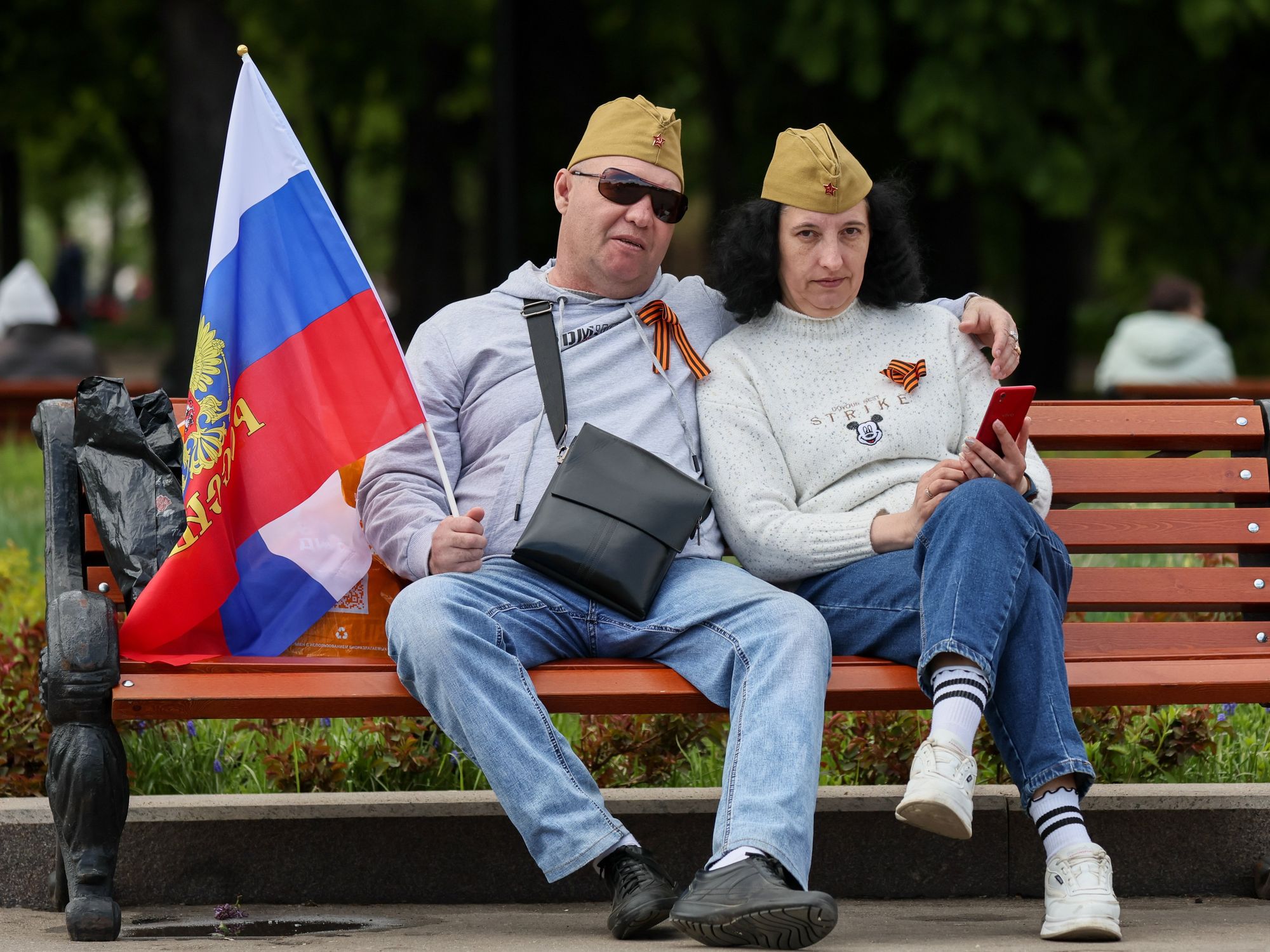 photo of a couple on a park bench in Moscow with man holding russian flag