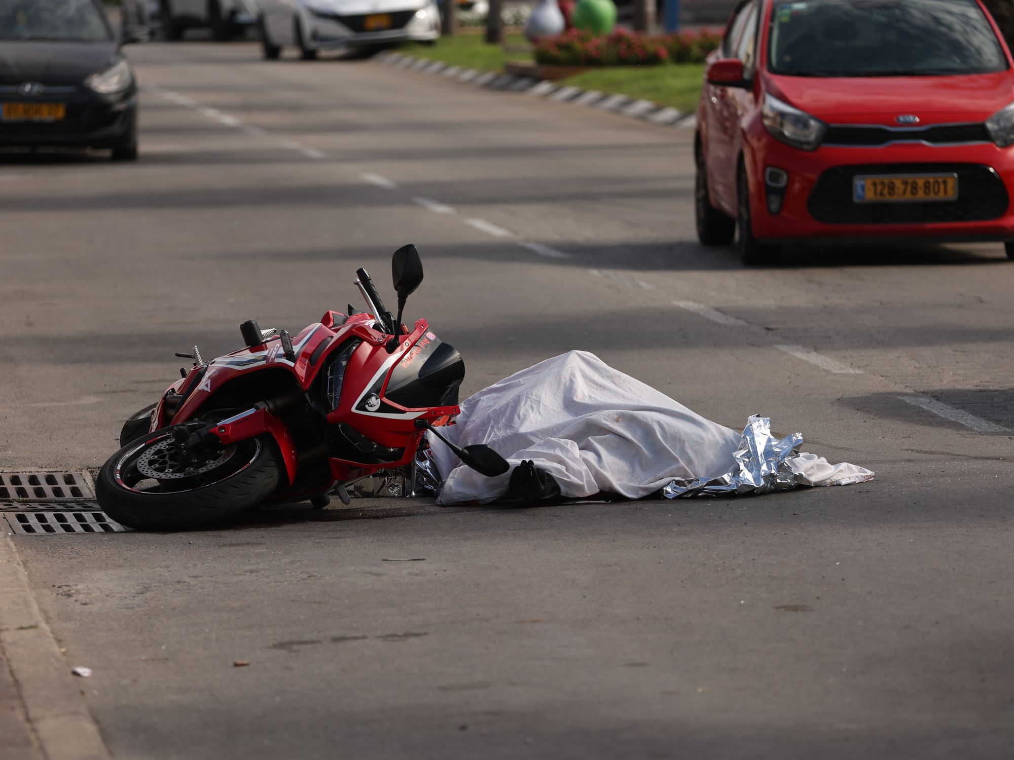 photo of a crashed motorcycle and a covered dead body