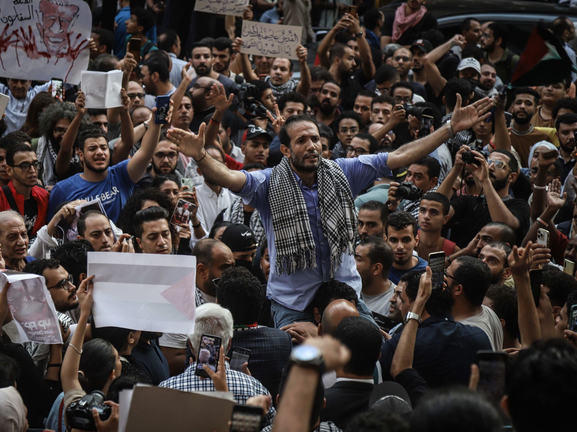 photo of a crowd of protesters holding signs and holding up their arms