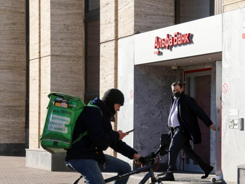 photo of a delivery guy on a bike and a man walking in front of a bank