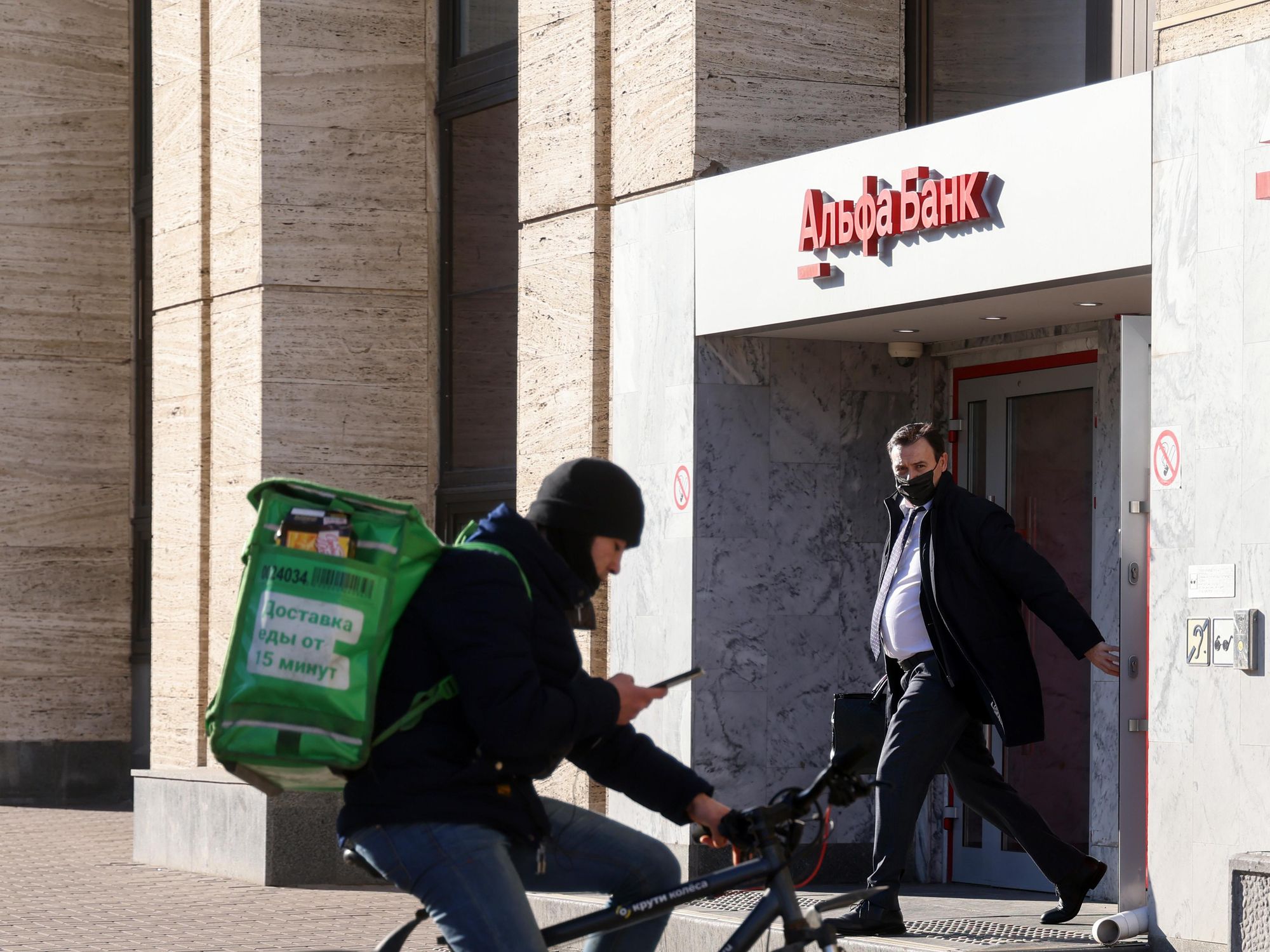 photo of a delivery guy on a bike and a man walking in front of a bank